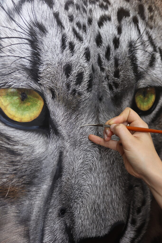 Artist painting a Snow Leopard in an example of realistic art.
